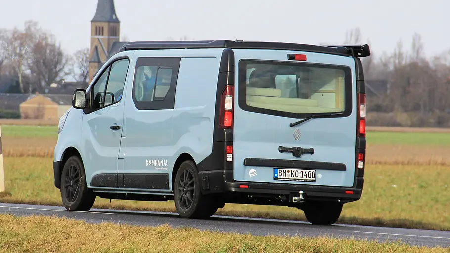 Das fahrdynamische Foto zeigt den Kompanja Eins von schräg hinten auf einer Landstraße.