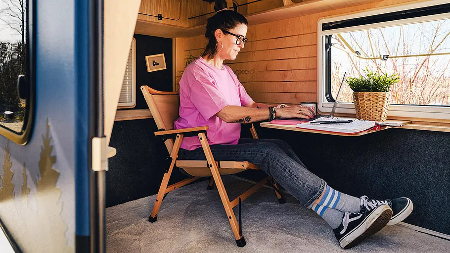 Eine Frau arbeitet am Ausklapptisch im Kuckoo Camper Bruno (2026).