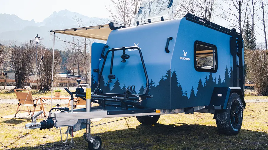 Die Außenaufnahme zeigt den stehenden Kuckoo Camper Max (2026) an einem See.
