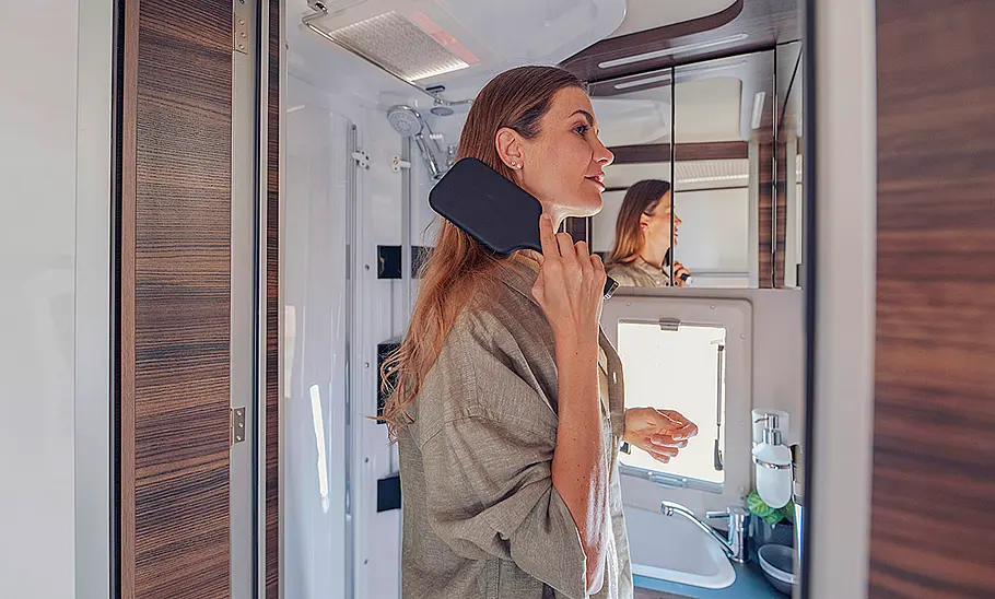 Laika Ecovip H 3109 (2024) Das Bild zeigt das Bad des Laika Ecovip H 3109 (2024) mit einer Person, die sich die Haare kämmt.