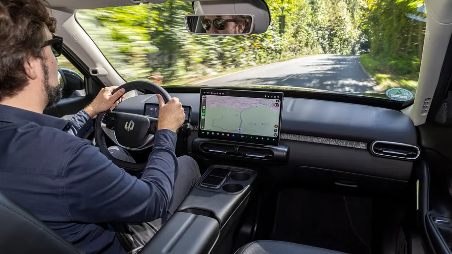 Ein Mann mit Sonnenbrille fährt auf einer Waldstraße. Auf dem zentralen Display im Leapmotor B03X ist eine Navigationskarte zu sehen.