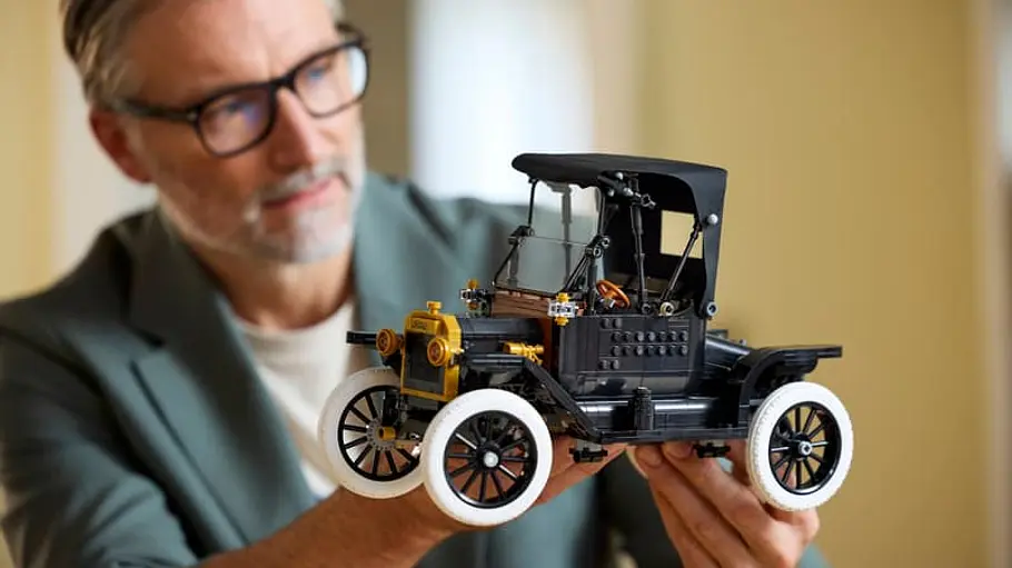 Eine Person hält das Lego-Icons-Modell Ford Model T hoch und schaut es sich an.