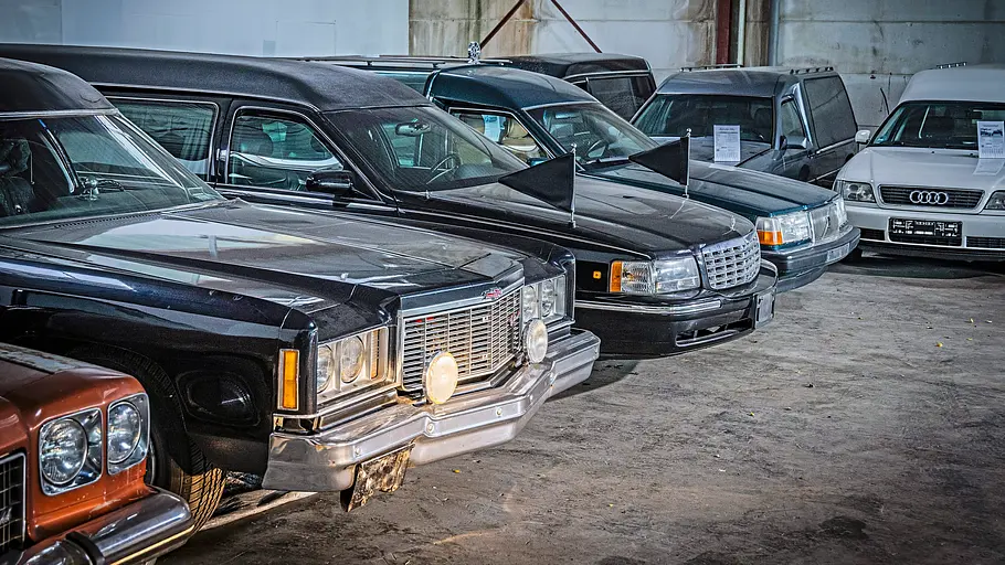 Diverse Leichenwagen nebeneinander parkend von schräg vorne fotografiert. 