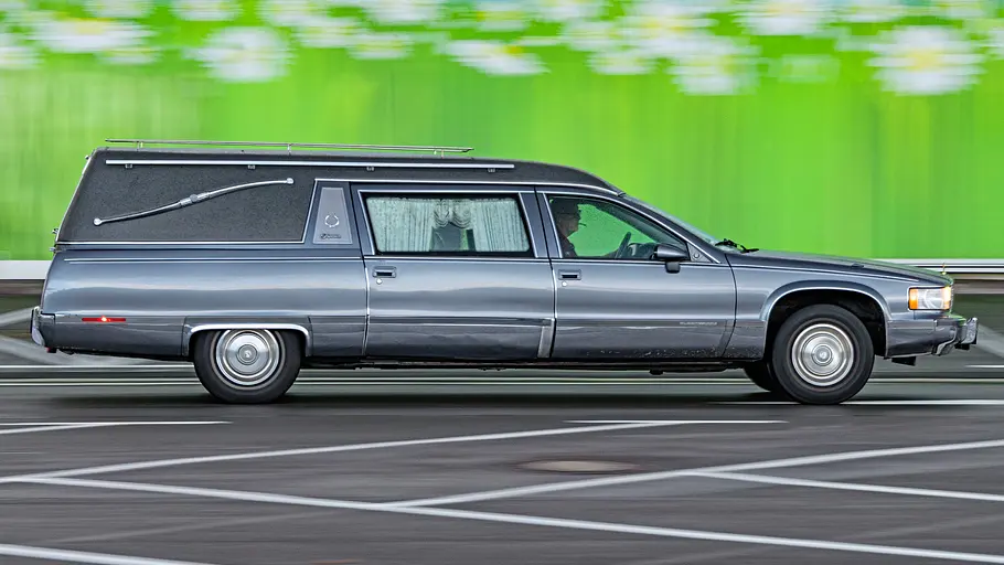 Cadillac Leichenwagen fahrend von der Seite fotografiert. 