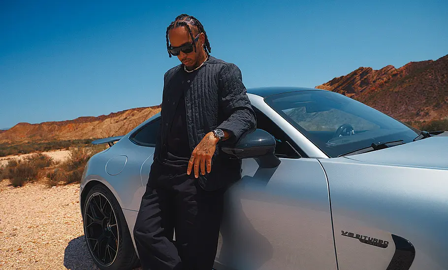 Rennfahrer Lewis Hamilton stehend vor einem Auto.