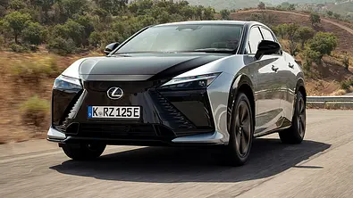 Der Lexus RZ fährt über eine Landstraße, fotografiert von schräg vorne. - Foto: Lexus