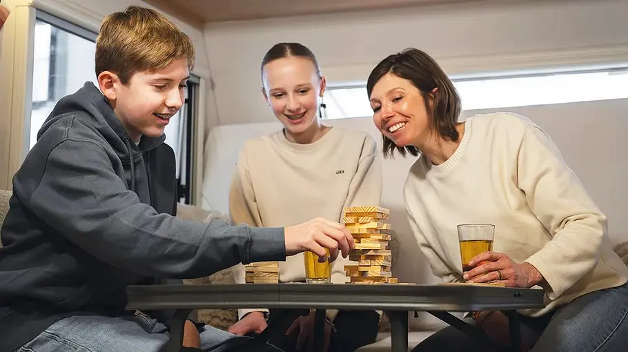 Eien Familie sitzt am Campingtisch im LMC E:Dero 350 D (2025) und spielt.