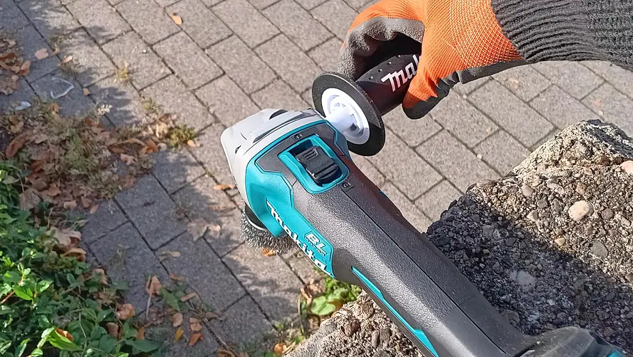Makita Akku-Flex DGA504 Die Hand eines Testers beim Abschrauben des Seitengriffs der Makita Akku-Flex DGA504.