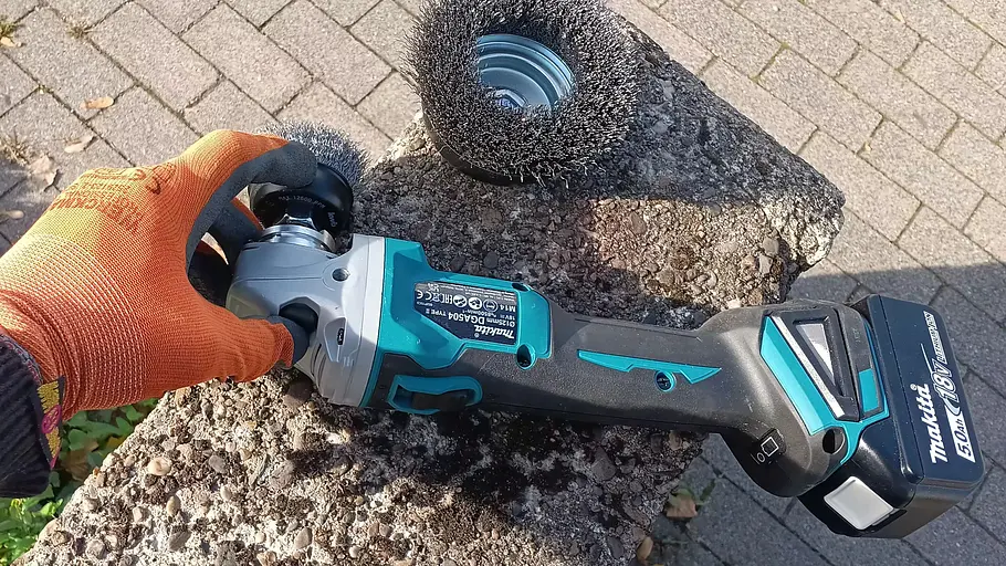 Makita Akku-Flex DGA504 Die Detailaufnahme zeigt die Hand eines Tester beim Bürstenwechsel der Makita Akku-Flex DGA504.