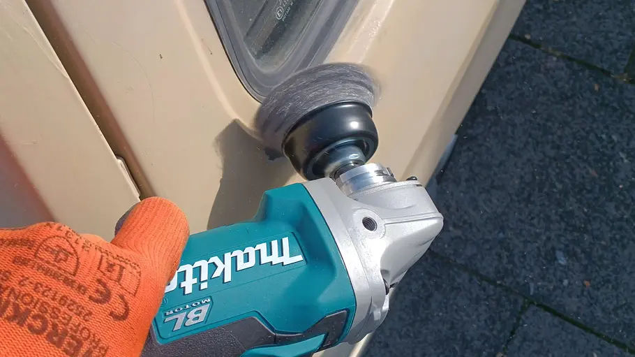 Makita Akku-Flex DGA504 Die Detailaufnahme zeigt die Makita Akku-Flex DGA504 im Einsatz am Blech eines älteren VW Polo.