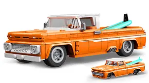 Das Bild zeigt den Mattel Brick Shop Custom Chevy Pick-up von schräg vorne links. Vor dem Klemmbaustein-Auto steht eine Diecast-Miniatur in kleinerem Maßstab. - Foto: Mattel