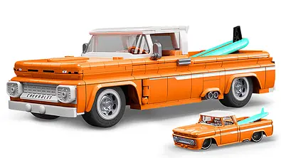 Das Bild zeigt den Mattel Brick Shop Custom Chevy Pick-up von schräg vorne links. Vor dem Klemmbaustein-Auto steht eine Diecast-Miniatur in kleinerem Maßstab. - Foto: Mattel