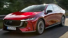 Der Mazda6e (2025) fährt über eine Landstraße, fotografiert von schräg vorne. - Foto: Mazda