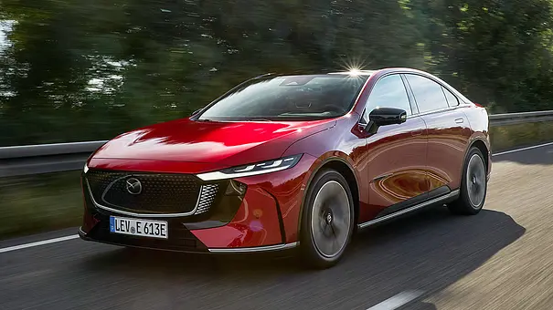 Der Mazda6e (2025) fährt über eine Landstraße, fotografiert von schräg vorne. - Foto: Mazda