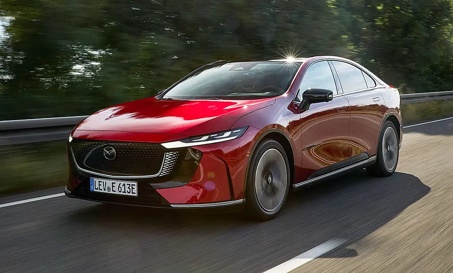 Der Mazda6e (2025) fährt über eine Landstraße, fotografiert von schräg vorne.