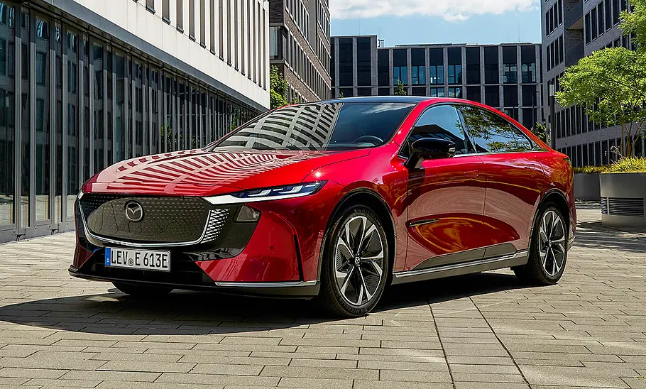 Der Mazda6e (2025) steht vor Bürogebäuden, fotografiert von schräg vorne.