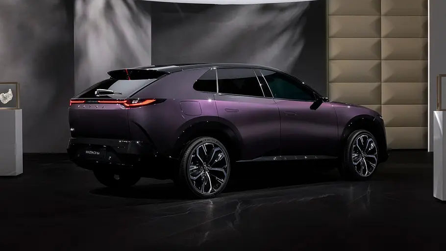 Der Mazda CX-6e (2026) stehend von schräg hinten in Studiokulisse fotografiert.
