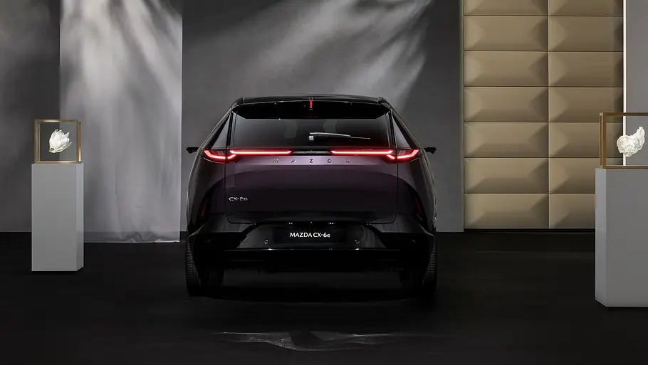 Der Mazda CX-6e (2026) stehend von hinten in Studiokulisse fotografiert.