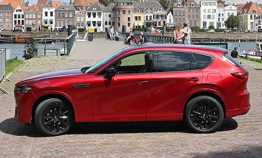 Der Mazda CX-60 steht vor der Kulisse einer niederländischen Kleinstadt, fotografiert von der Seite.