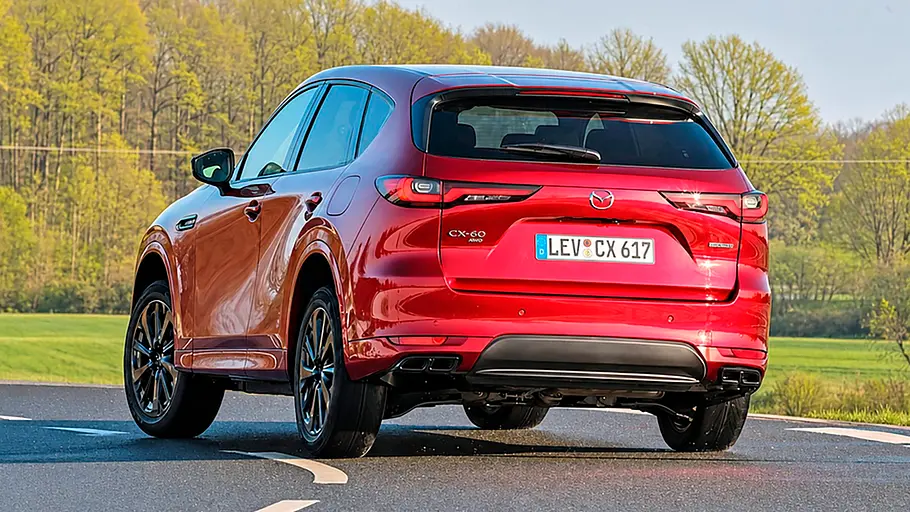 Der Mazda CX-60 e-Skyactiv D 254 AWD in einer Linkskurve fahrend von schräg hinten links.