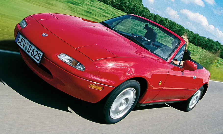 Der Mazda MX-5 fahrend auf einer Straße mit offenem Verdeck.