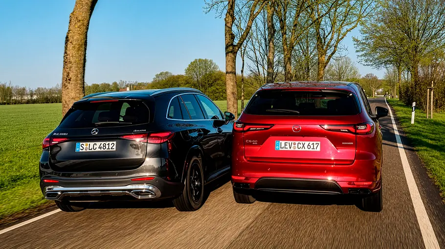 Mercedes GLC 450 d 4Matic und Mazda CX-60 e-Skyactiv D 254 AWD auf einer Landstraße fahrend von schräg hinten.