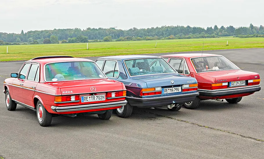 Mercedes 230 E/BMW 525i/Audi 200 5E statisch von schräg hinten fotografiert.