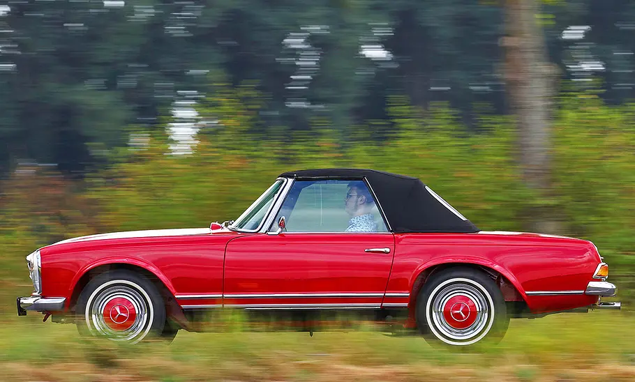 Der Mercedes 280 SL (W113) fahrend seitlich.