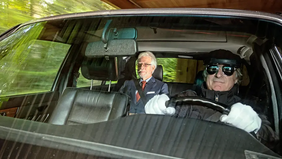 Mercedes 420 SEL Fahrer und Mitfahrer im Auto sitzend von vorne durch die Windschutzscheibe fotografiert.