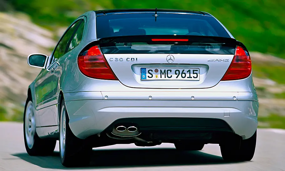 Der Mercedes C 30 CDI AMG Sportcoupé fährt in eine Kurve, von schräg hinten fotografiert.