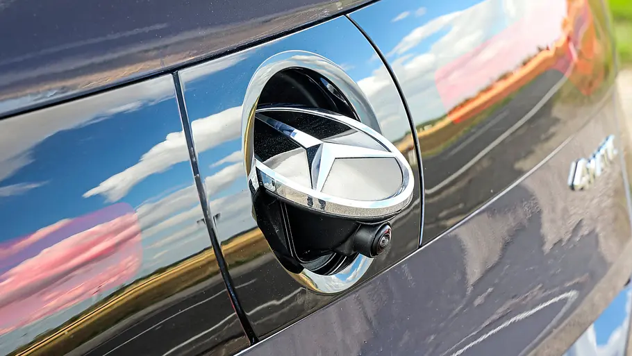 Test Mercedes C 400 4Matic elektrisch Am Heck des C 400 4Matic elektrisch ist das Sternemblem ausgeklappt und eine Kamera sichtbar. Himmel und Wolken spiegeln sich im Lack.