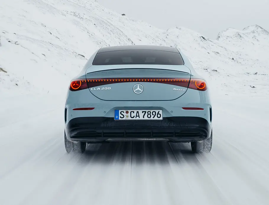Mercedes CLA Hybrid Fahrendes Auto auf einer verschneiten Straße, mit Ansicht auf das Heck.