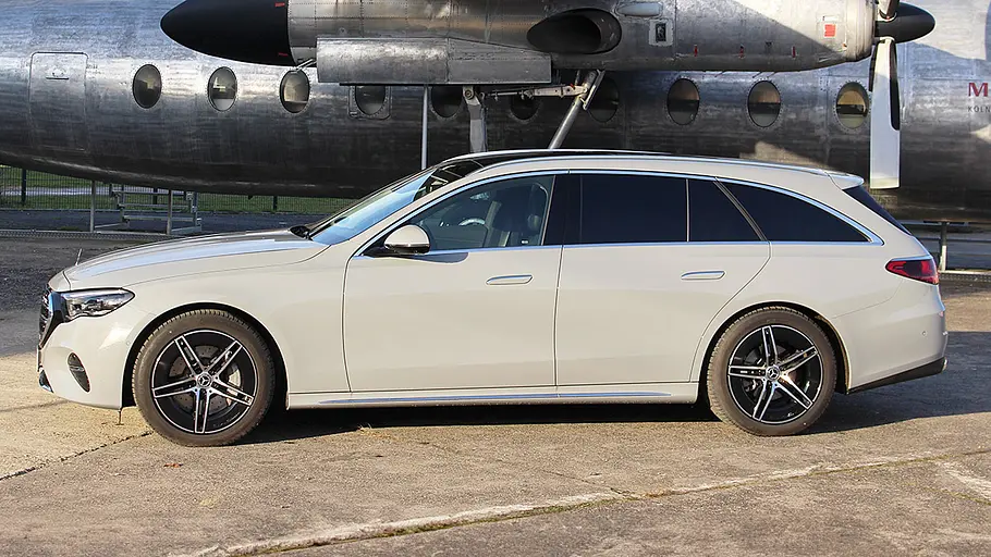 Mercedes E 220 d 4Matic T-Modell Das Mercedes E 220 d 4Matic T-Modell seht vor einem alten Flugzeug, von links fotografiert.