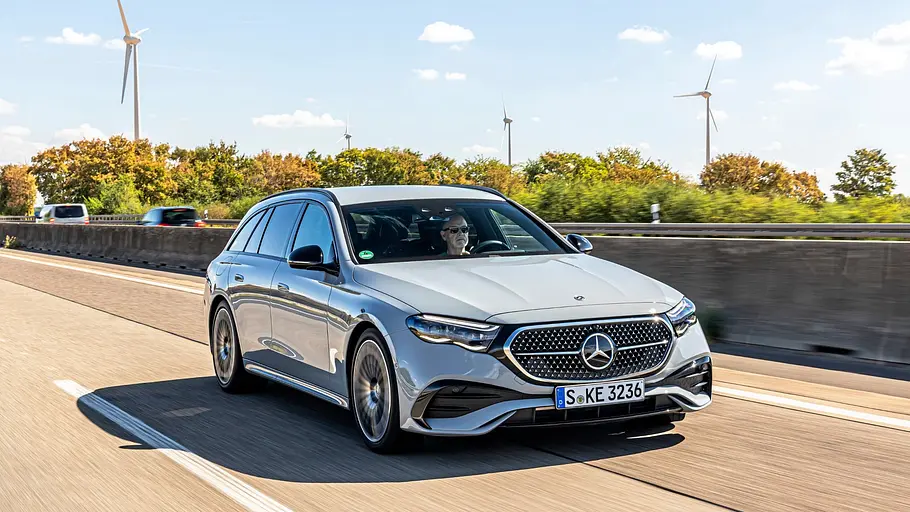 Silberner Mercedes E 450 d 4Matic T-Modell in der Fahraufnahme auf der Autobahn, dahinter Windräder