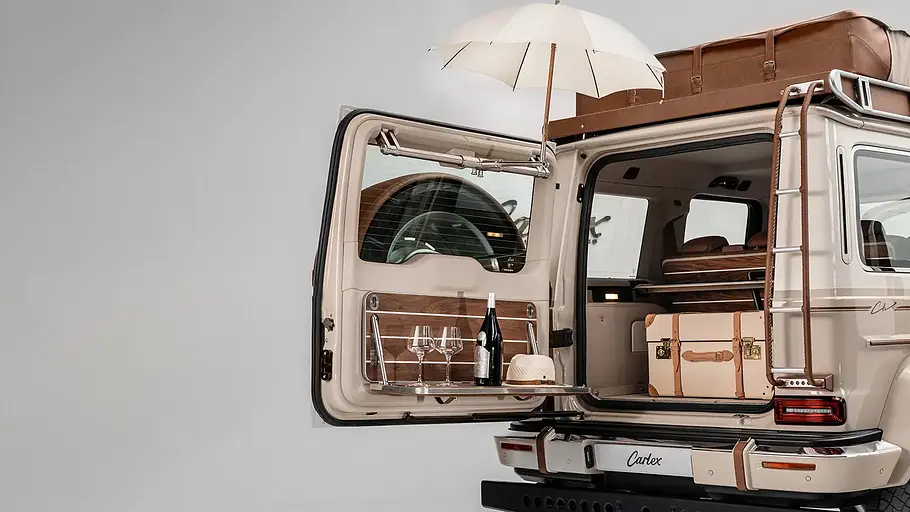 Geöffnete Hecktür mit Klapptisch des Mercedes G Safari Royal von Carlex Design, fotografiert von rechts hinten.
