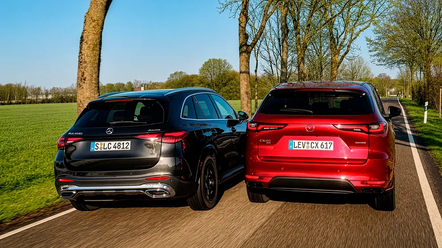 Mercedes GLC 450 d 4Matic und Mazda CX-60 e-Skyactiv D 254 AWD auf einer Landstraße fahrend von schräg hinten.