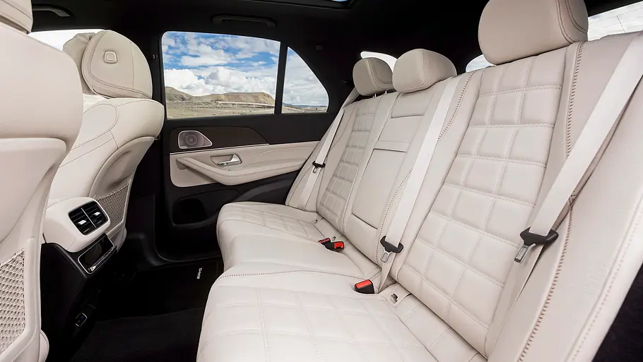 Mercedes GLE 580 4Matic Modellpflege Fahrbericht Der Innenraum des Mercedes GLE mit heller Lederrückbank, drei Kopfstützen, Sicherheitsgurten und Panoramaglasdach ist zu sehen.