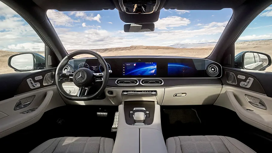 Mercedes GLE 580 4Matic Modellpflege Fahrbericht Der Mercedes GLE Innenraum hat helle Ledersitze und ein breites digitales Armaturenbrett. Durch die Fenster ist eine karge Landschaft zu sehen.