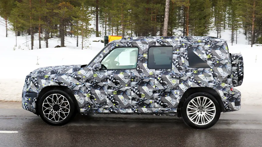 Mercedes kleine G-Klasse Erlkönig Der Erlkönig der Mercedes kleine G-Klasse fahrend im Profil von links. Im Hintergrund liegt Schnee.