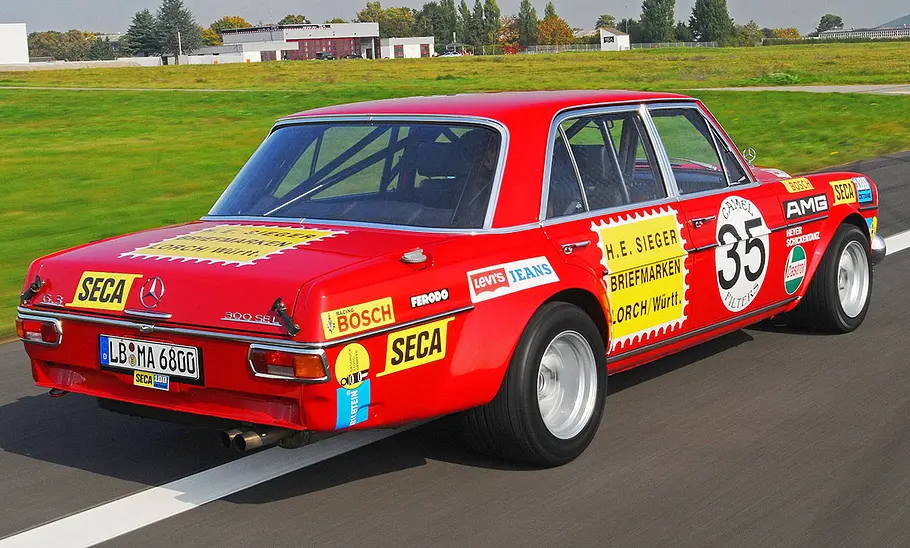 Mercedes 300 SEL AMG Rote Sau Der Mercedes 300 SEL AMG Rote Sau fahrend von schräg hinten