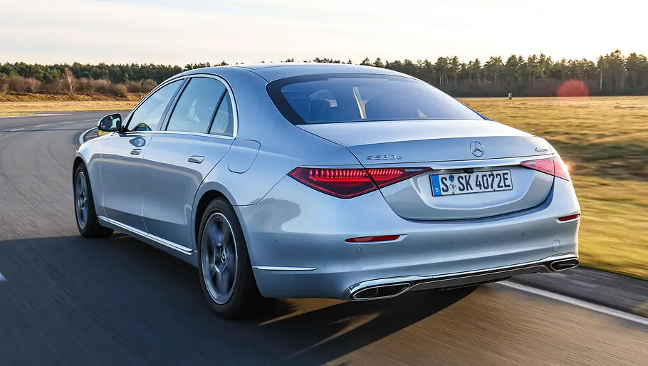 Der Mercedes S-Klasse Lang fährt auf einer Straße, von hinten links fotografiert.