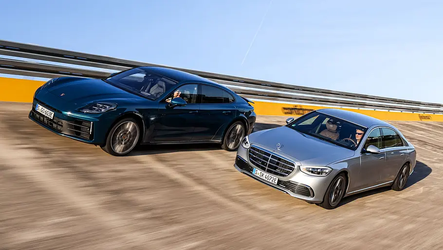 Porsche Panamera Executive und Mercedes S-Klasse fahren nebeneinander durch eine Steilkurve, von vorne fotografiert.