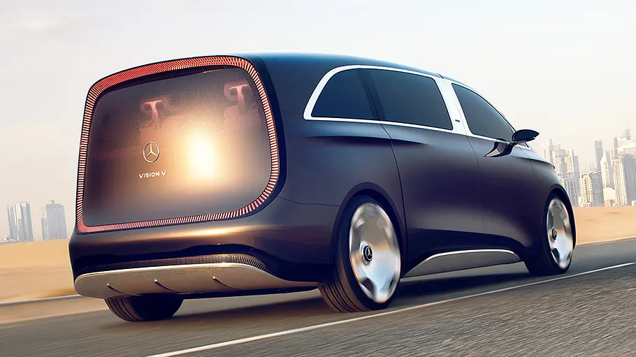 Der Mercedes Vision V (2025) fährt vor Wüsten- und Skyline-Hintergrund durch Dubai, von hinten rechts fotografiert.