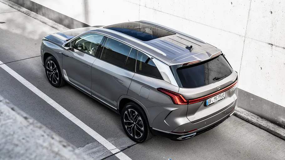Der MG S9 PHEV steht vor einer Betonwand, obersichtig von hinten links fotografiert.
