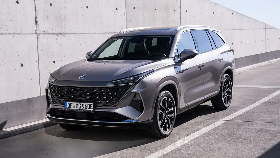 Der MG S9 PHEV steht vor einer Betonwand, von vorne links fotografiert.