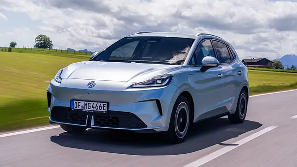 Der MG4 EV Urban fährt auf einer Landstraße, von vorne links fotografiert. - Foto: MG