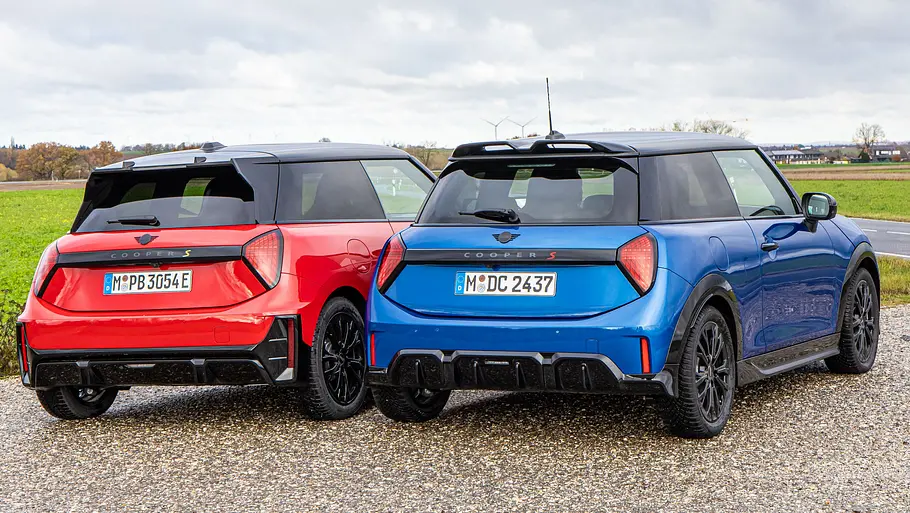 Mini Cooper S und Cooper SE Die beiden Mini Cooper stehen nebeneinander auf Asphalt und es wurde von schräg hinten fotografiert.