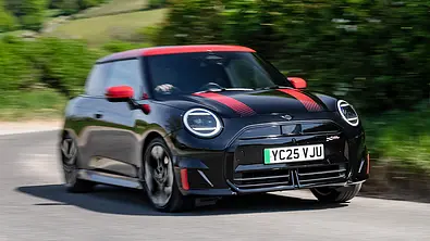 Der Mini JCW Electric (2025) fährt dynamisch durch eine Kurve, fotografiert von schräg vorne. - Foto: Mini
