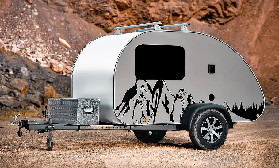 Miniatouring Mini-Caravan M22 (2026) steht im Gelände, ohne Zugfahrzeug. Ansicht von links.