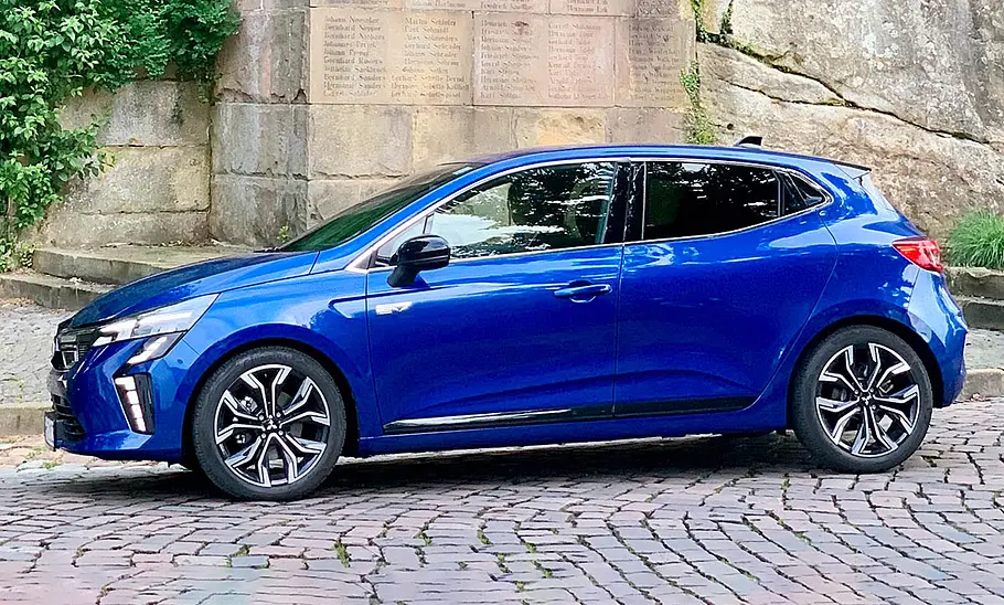 Mitsubishi Colt Hybrid 1.6 steht auf Kopfsteinpflaster vor einer alten Mauer, Ansicht von der linken Seite.